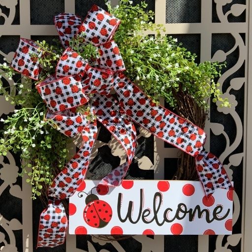 Grapevine wreath with greenery and a welcome sign with ladybugs and a matching ladybug bow